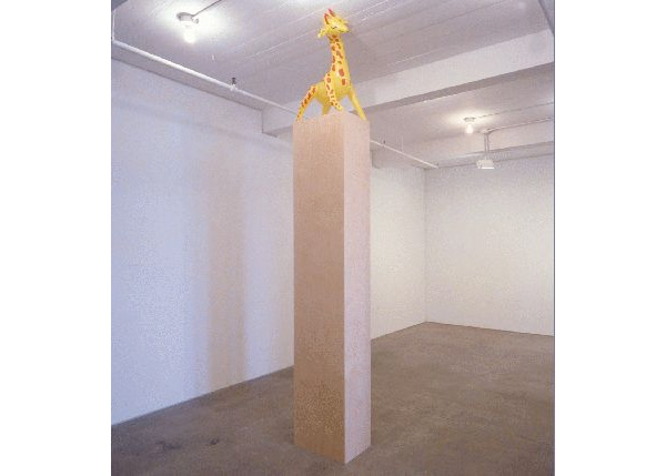 Giraffe with no title but with a pedestal so high that it makes her head bump into the ceiling